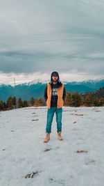 Portrait of man standing on snow covered field against sky