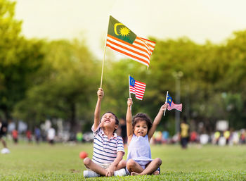 Cheerful siblings holding malaysian flags