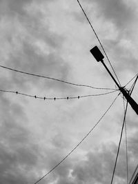 Low angle view of silhouette birds on cable against sky