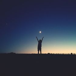 Silhouette boy standing on field against sky at dusk