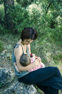 Rear view of mother and daughter sitting on tree