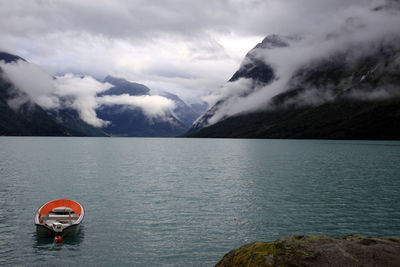Lone boat in calm lake against clouds