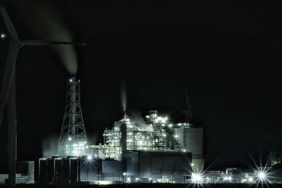 Illuminated factory against sky at night