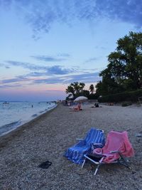 Deck chairs on beach against sky