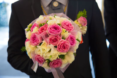 Mid section of a man holding bouquet