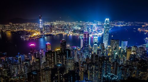 High angle view of river amidst modern city buildings at night