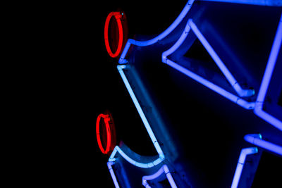 Low angle view of illuminated lighting equipment against black background