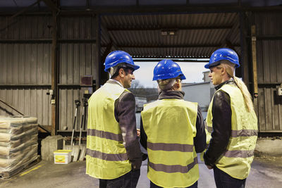 Rear view of manual workers discussing in cement warehouse