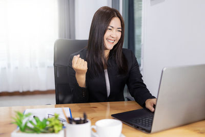 Young woman using phone while sitting on table