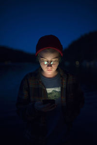 Teenage girl using mobile phone while standing against sky in olympic national park at night