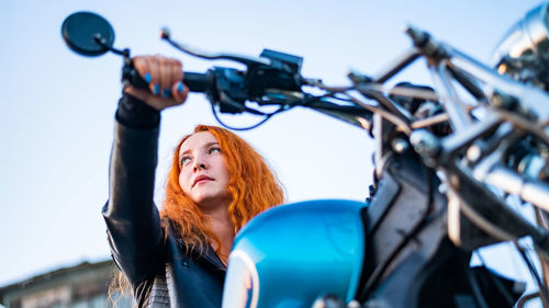 Portrait of woman holding camera against sky