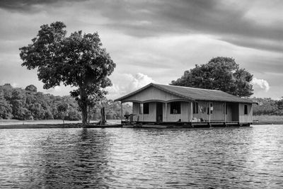 House by lake and buildings against sky