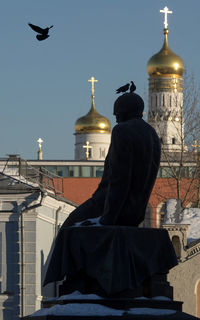 Rear view of statue against sky in city