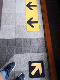 Low section of person standing by arrow symbol on street