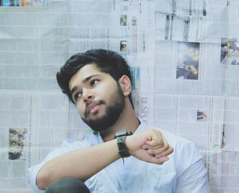 Portrait of young man standing against wall