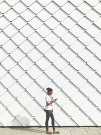 Full length of woman standing against wall