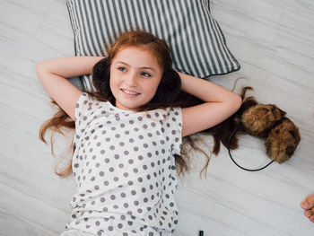 High angle view of smiling girl lying on floorboard at home