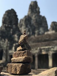 Stack of sculpture on rock against temple