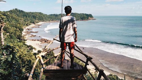 Rear view of man looking at sea while standing on observation point