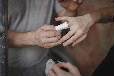 Caucasian men bandaging an injured finger at a construction site.