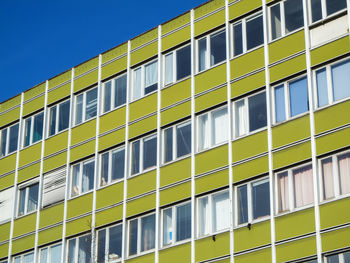 Facade of an older office building in a berlin outskirts in front of a blue sky.