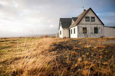 Abandoned house in field against sky