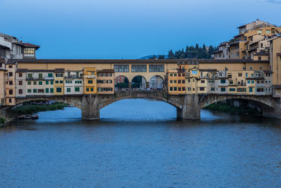 Arch bridge over river against buildings in city