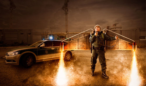 Man standing on illuminated car at night