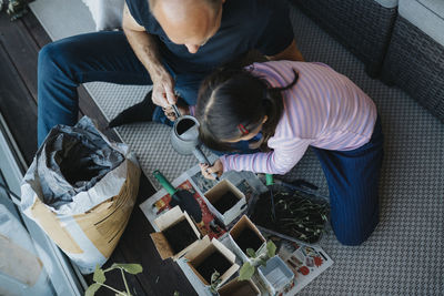 Father and daughter bonding over planting seedlings on balcony