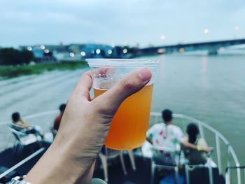 Cropped hand of man holding drink on boat