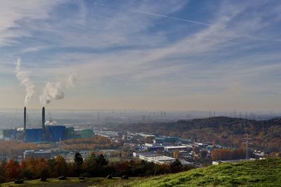 Smoke emitting from factory against sky