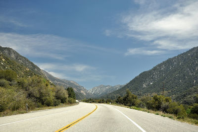 Empty road by mountains against sky