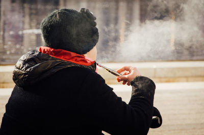 Rear view of woman smoking e-cigarette