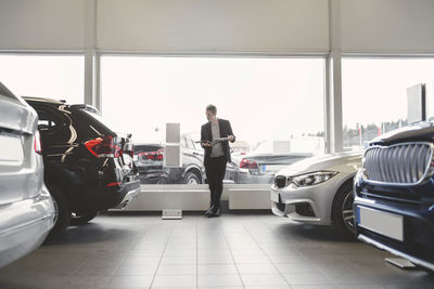 Full length of man reading brochure in car dealership store