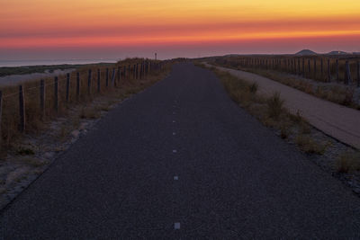 Road amidst land against sky during sunset