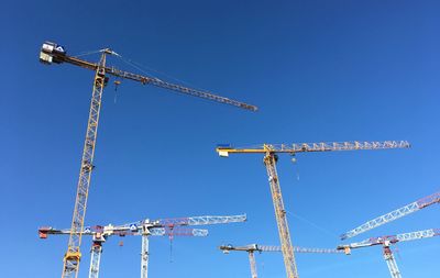 Low angle view of crane against clear blue sky