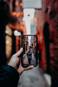 Man taking photo on cellphone of woman in alleyway