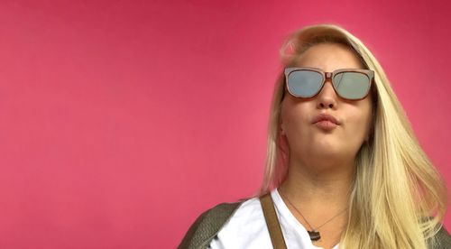 Close-up of beautiful young woman against pink background