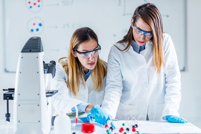 Female scientists examining chemical in laboratory