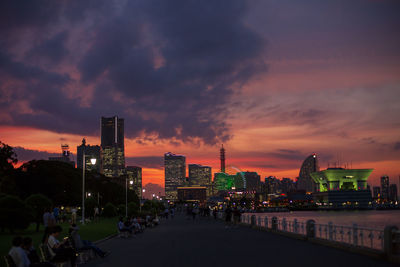 Illuminated city buildings against sky during sunset