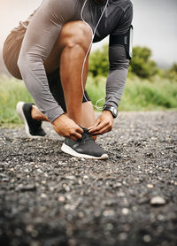 Low section of man tying shoelace