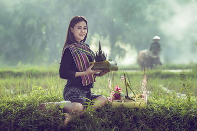 Full length of young woman with religious offerings on field against sky