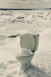 Abandoned commode on snow covered landscape