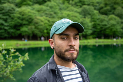 Portrait of young man standing against lake