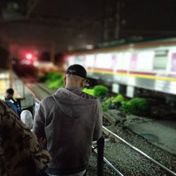 Rear view of man standing on train at night