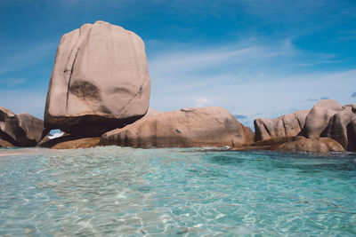 Rock formations in sea against blue sky