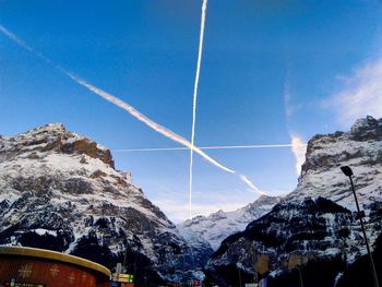 Low angle view of snowcapped mountains against blue sky