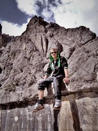 Portrait of man sitting on mountain against sky