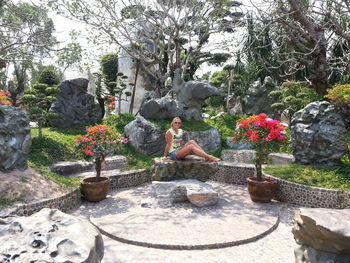 Man sitting on rock by fountain against trees