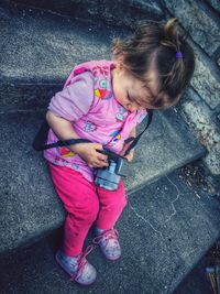 High angle view of girl holding camera on steps